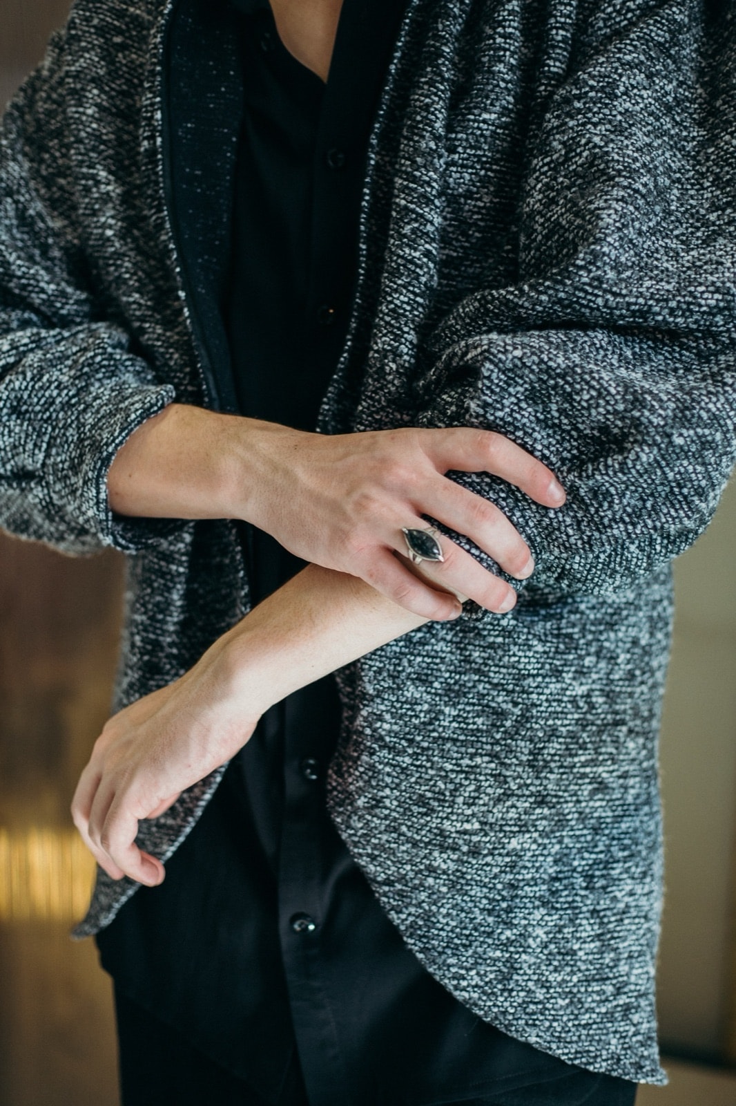 Detalle de la textura del tapado gris oversize de Atelier Molina, primer plano sobre modelo con las manos cruzadas.