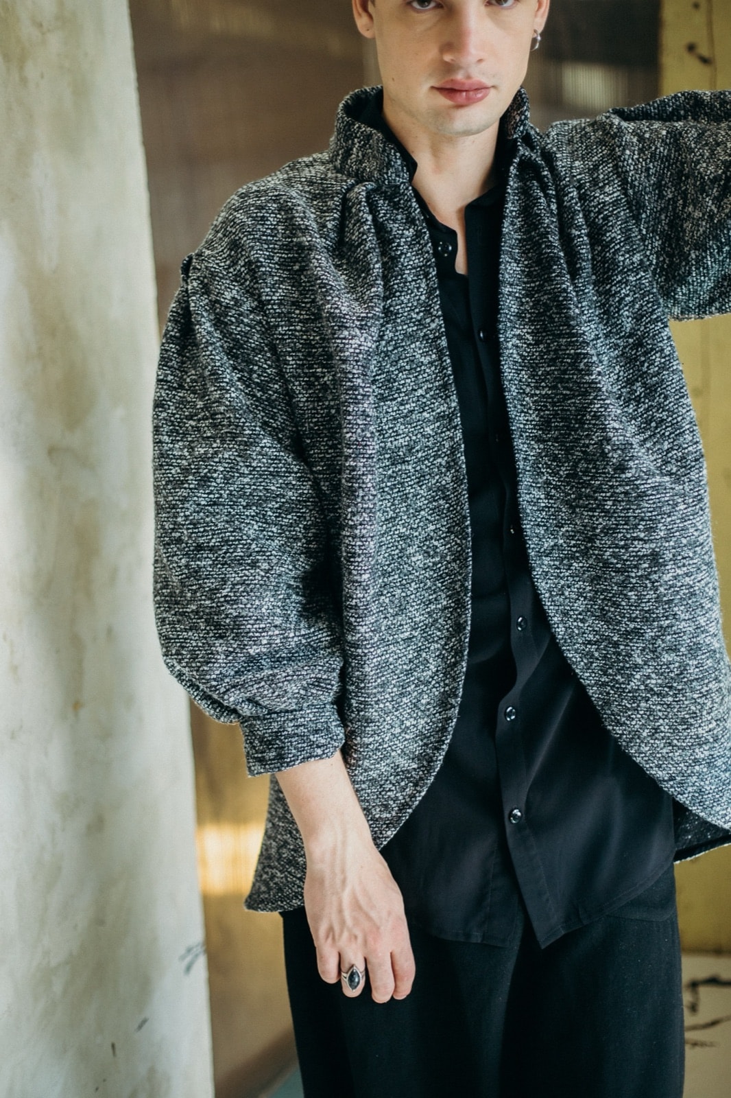 Detalle del cuello y la solapa del tapado gris oversize de silueta tulip de Atelier Molina, sobre modelo con camisa negra.