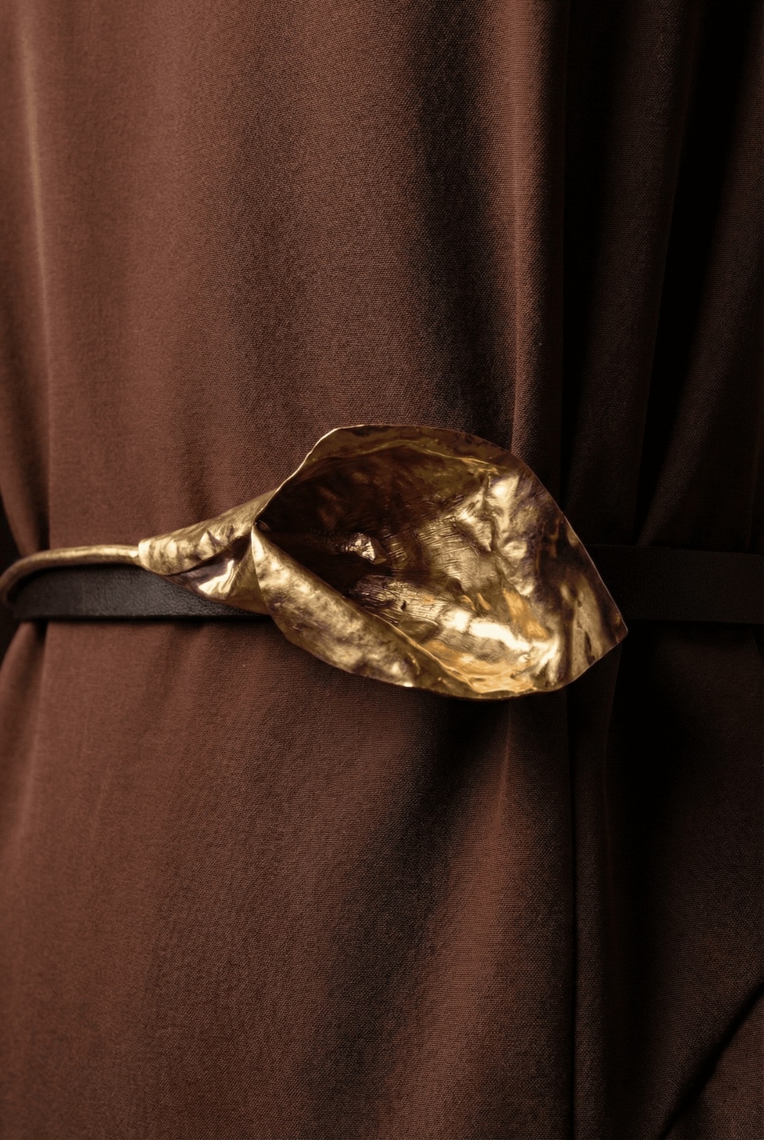 Detalle del cinturón escultórico dorado con forma de cala del Vestido Chocolate con Tablas de Atelier Molina.