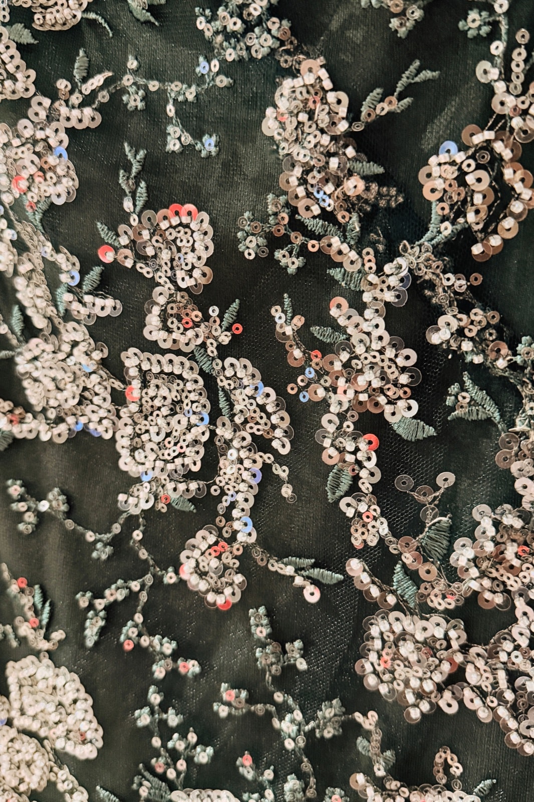 Detalle del bordado floral sobre tul verde: lentejuelas nacaradas, canutillos y hojas en hilo, con puntos rojos y celestes. Vestido corto de Atelier Molina, Buenos Aires