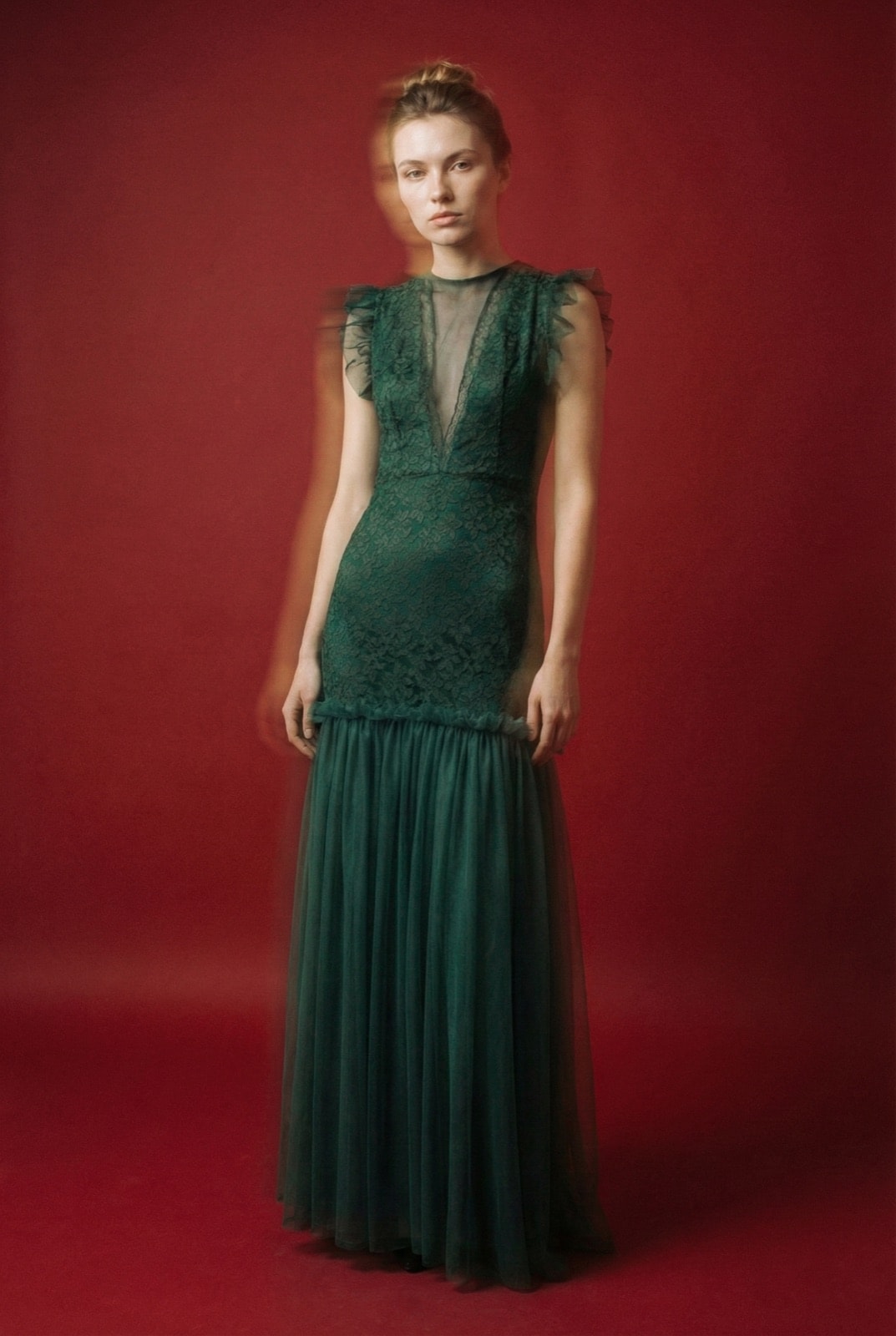 Vestido de encaje con ruffles verde sobre modelo de cuerpo entero, vista frontal mostrando el escote profundo y la falda de tul.
