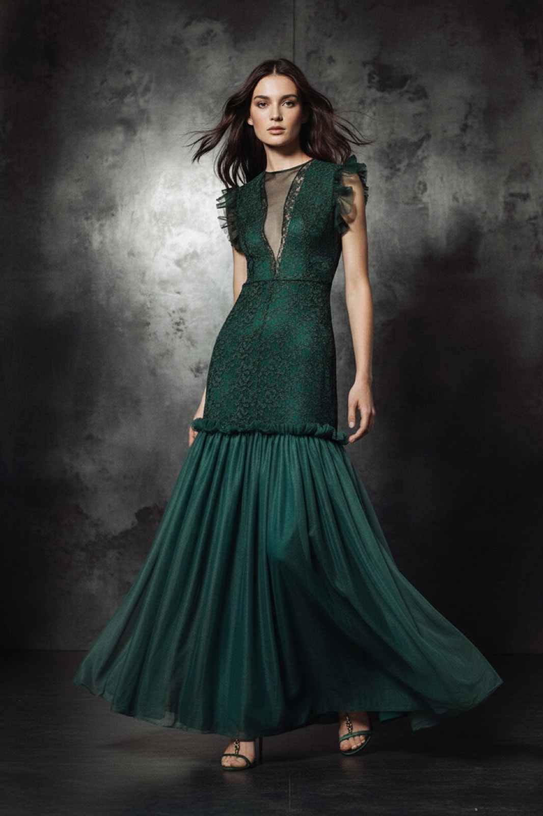 Vestido de encaje con ruffles verde sobre modelo, vista frontal completa en un ambiente con paredes texturadas oscuras.