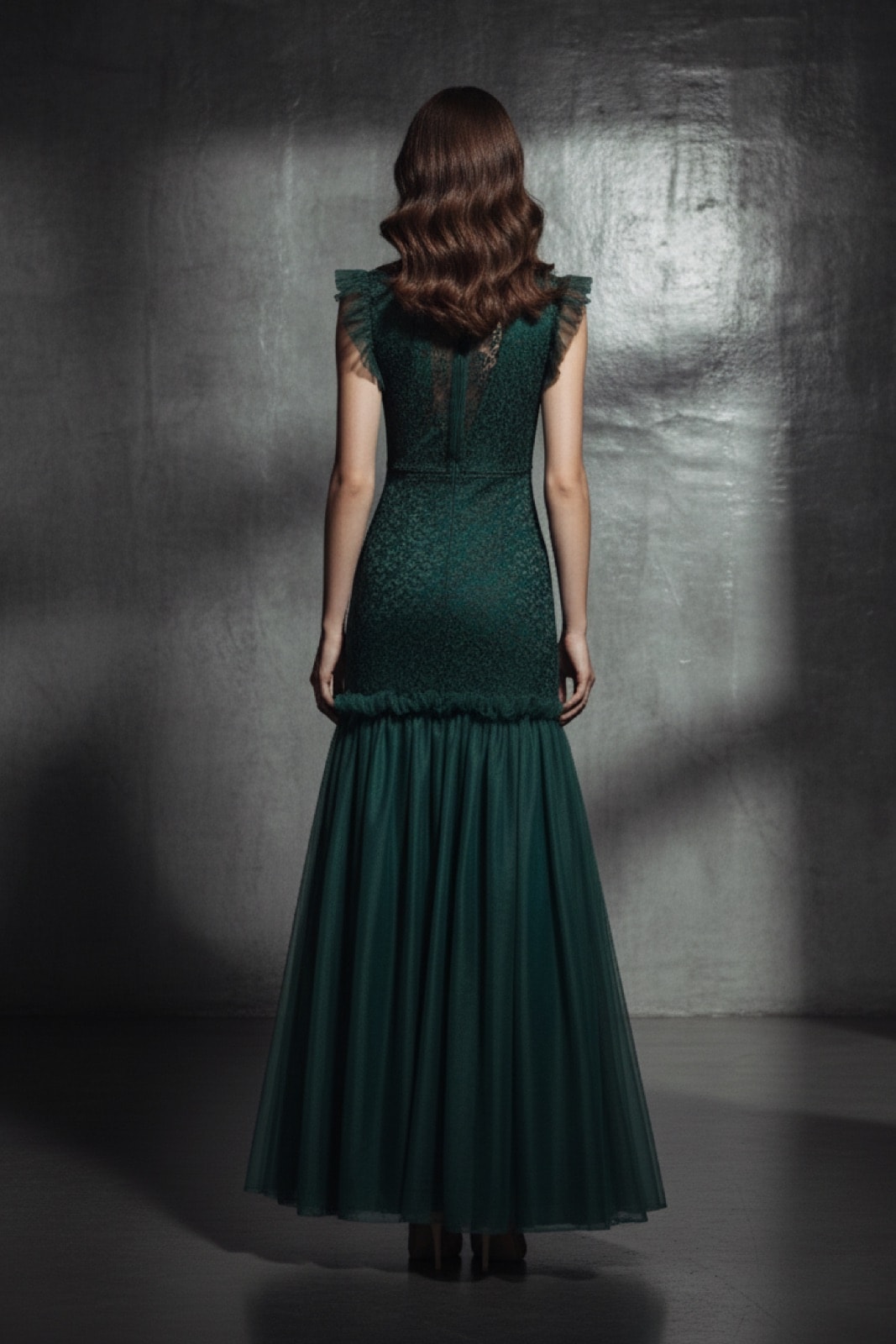 Vestido de encaje con ruffles verde sobre modelo, vista de espalda mostrando el volado en los hombros y el vuelo de la falda.