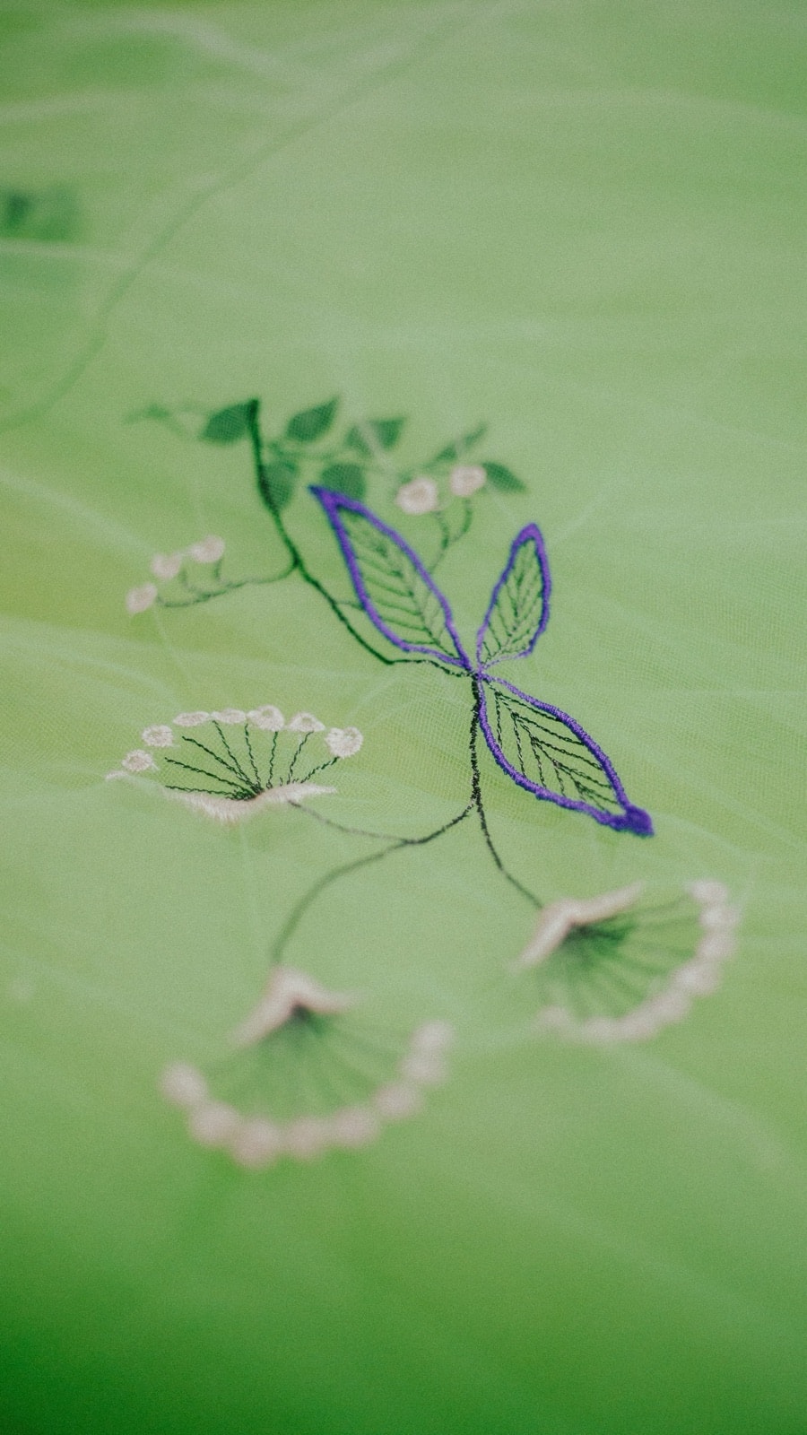 Primer plano del bordado de flores y hojas en la falda de tul verde del vestido Emerald Garden, con detalle en violeta.