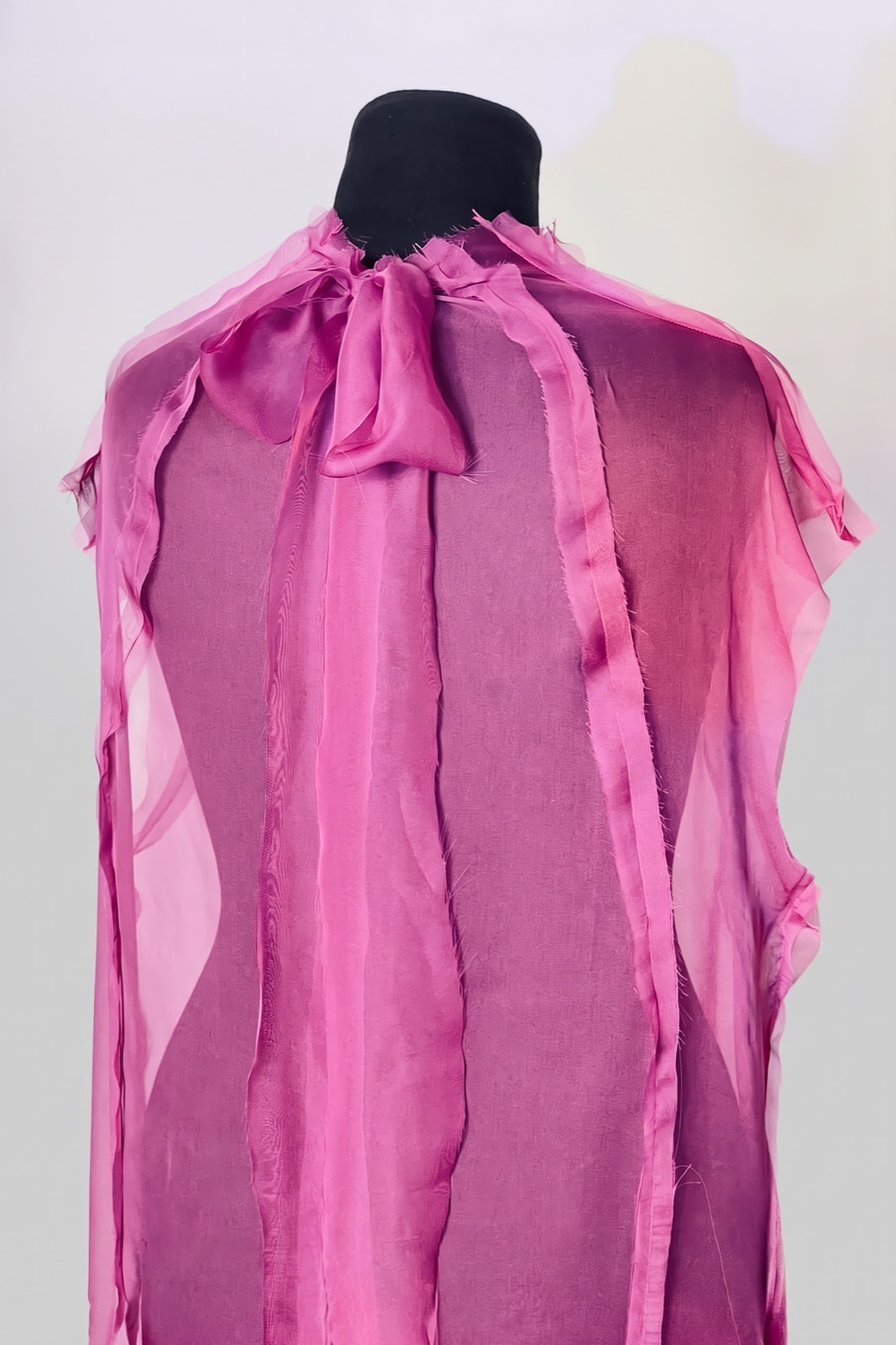 Espalda del vestido de muselina fucsia con moño de seda en el cuello y costuras expuestas