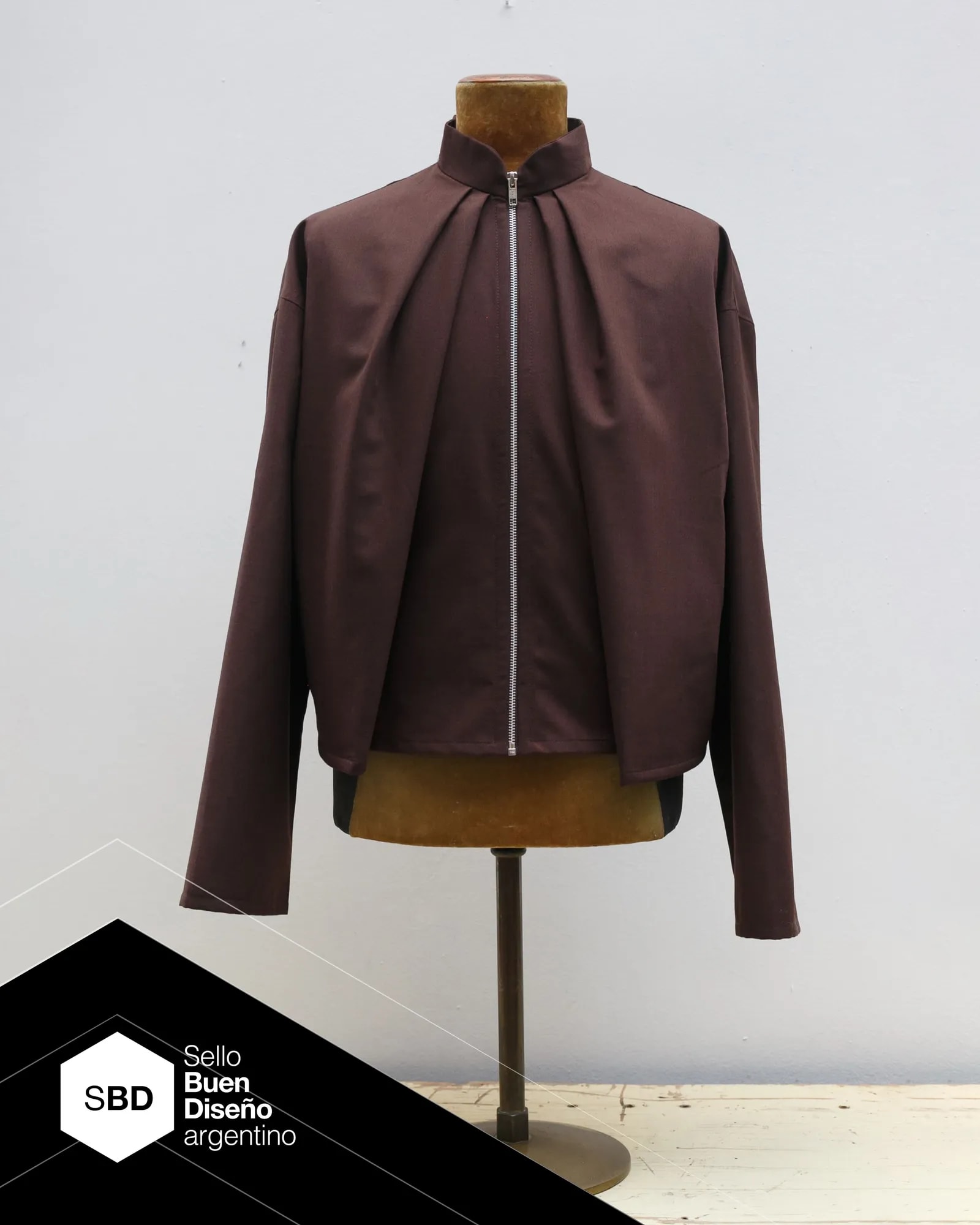 Molina Jacket in chocolate brown wool cloth, with two front pleats set at 45 degrees. Part of the Atelier Molina PLIEGO line, Argentine Good Design Seal 2026, made in Buenos Aires.