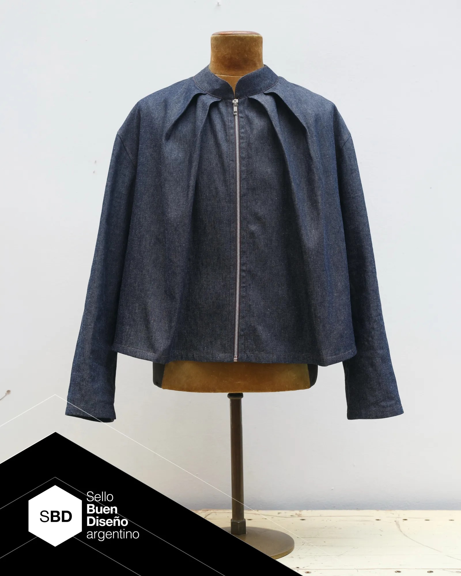 Molina Jacket in seven ounce indigo raw cotton denim, with two front pleats set at 45 degrees. Part of the Atelier Molina PLIEGO line, Argentine Good Design Seal 2026, made in Buenos Aires.