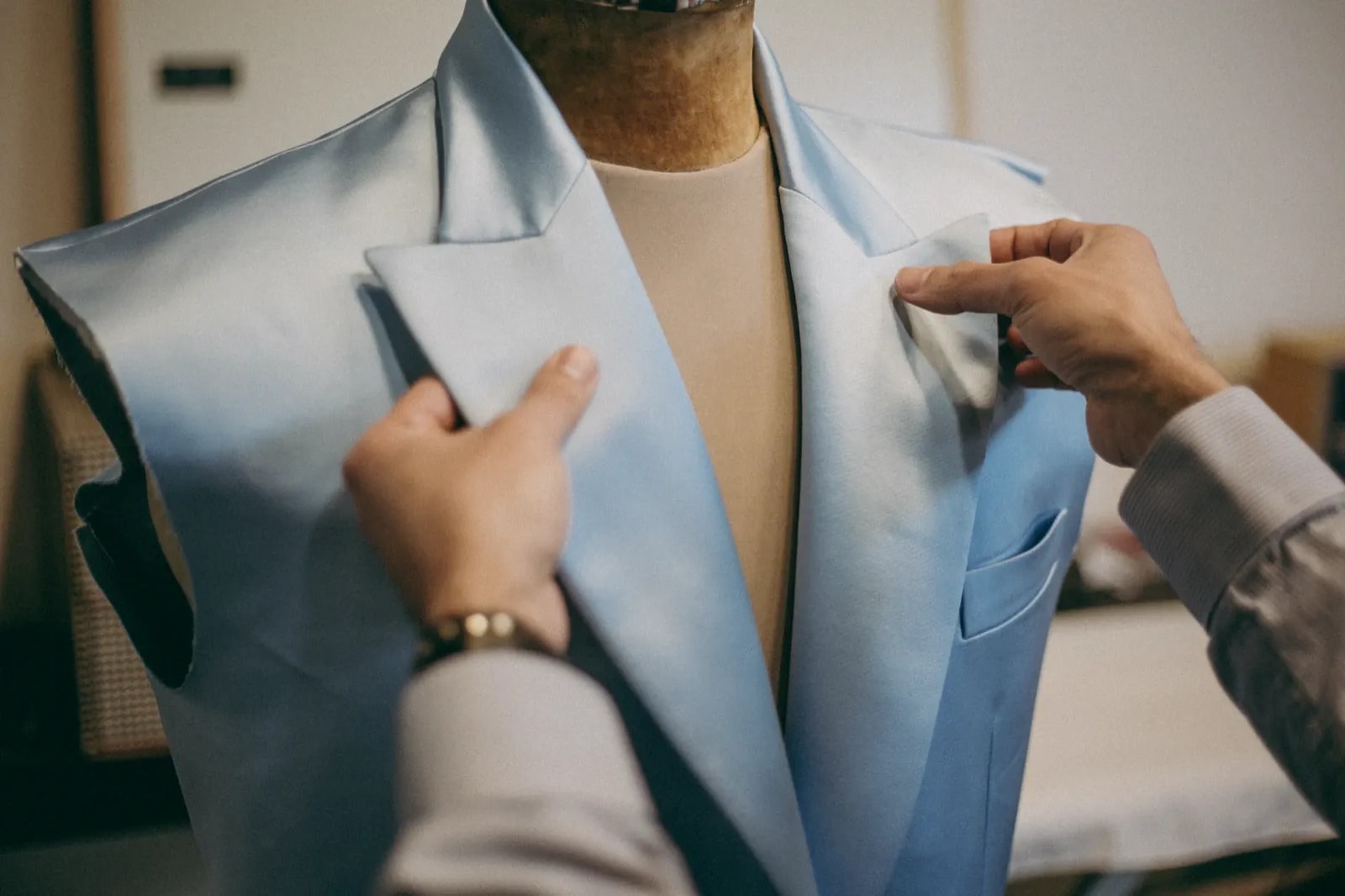 Las manos de Carlos Molina armando la solapa de un saco de crepe de seda celeste a medida, en el atelier de Buenos Aires