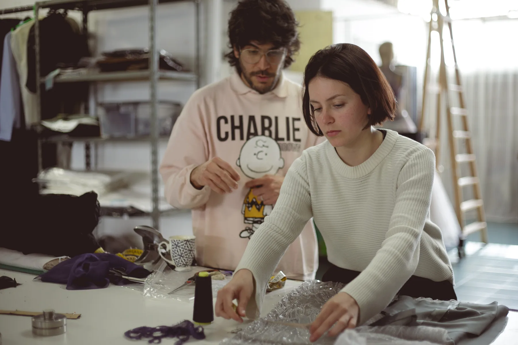 Dos estudiantes de Diseño de Indumentaria de la FADU (UBA) trabajando sobre un tul bordado en la mesa de corte del atelier de Buenos Aires