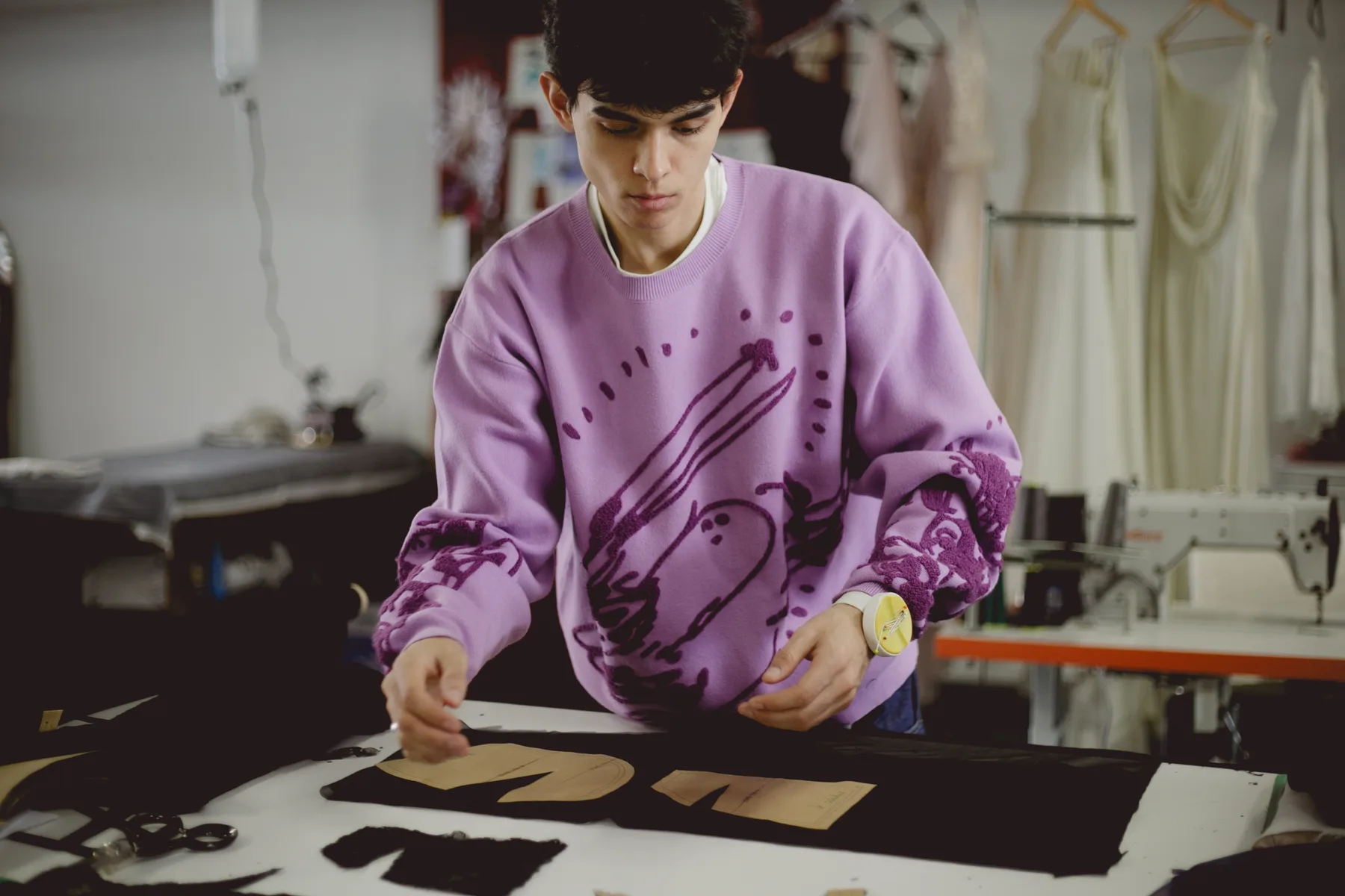 Estudiante de Diseño de Indumentaria de la FADU (UBA) acomodando moldes de papel sobre la tela antes de cortar, en el atelier de Buenos Aires