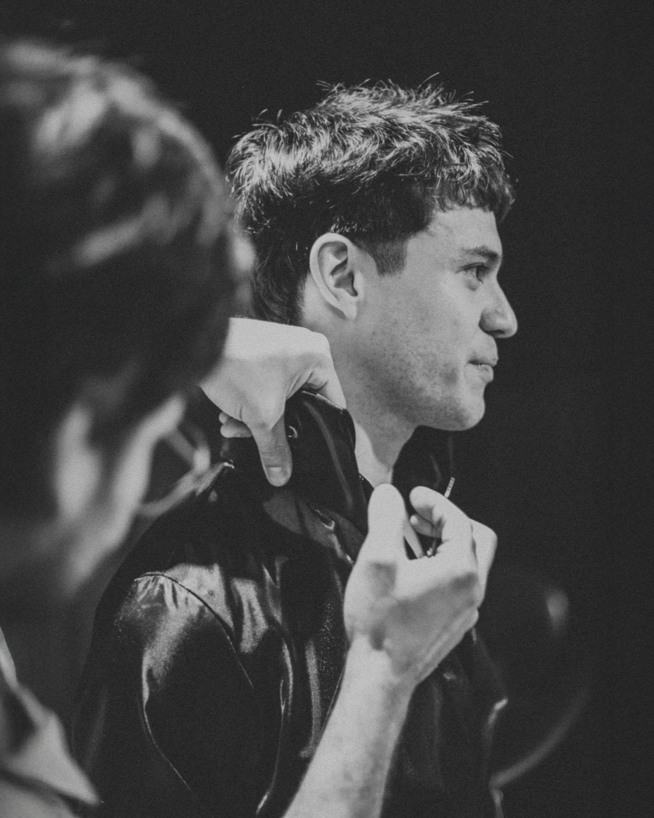 Alan Lez in profile backstage while Carlos Molina adjusts the collar of his Atelier Molina jacket