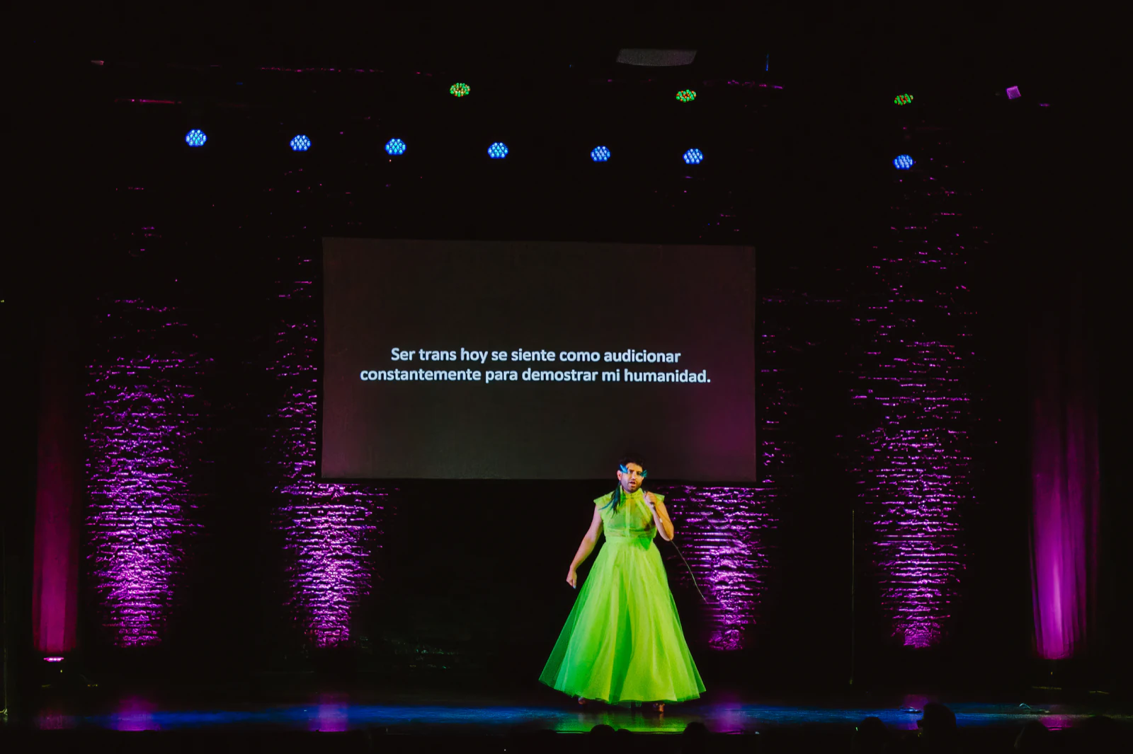 Alok V Menon on stage in Buenos Aires wearing the green tulle gown by Atelier Molina, in front of a projected line
