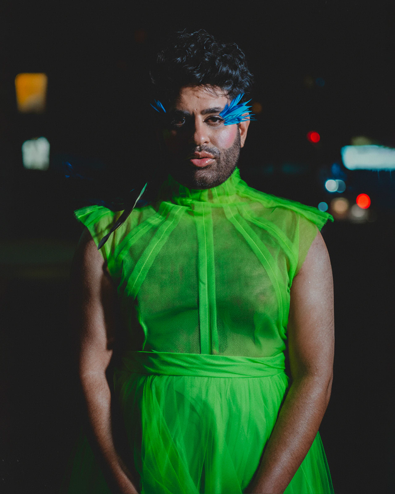 Alok V Menon leaning against a metal shutter in the green tulle gown by Atelier Molina