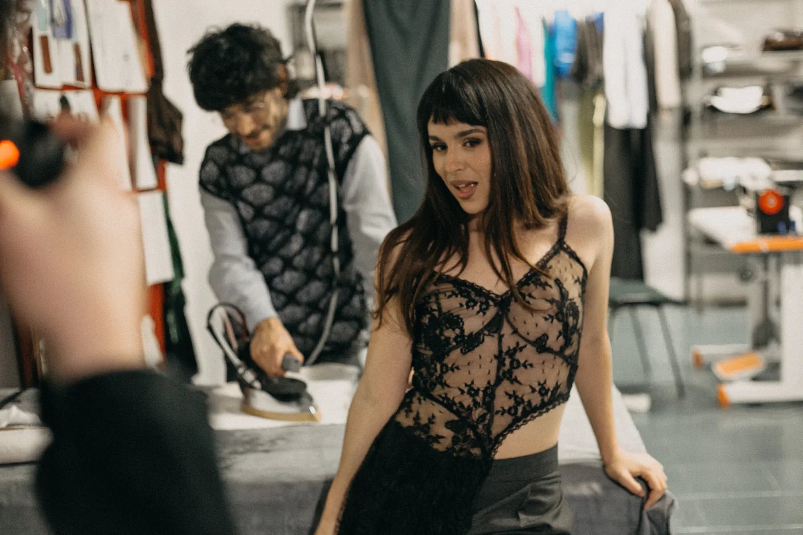 Evitta Luna in a black lace blouse and tailored trousers by Atelier Molina in the Buenos Aires workshop; behind her, Carlos Molina pressing a garment. Photo published by Clarín