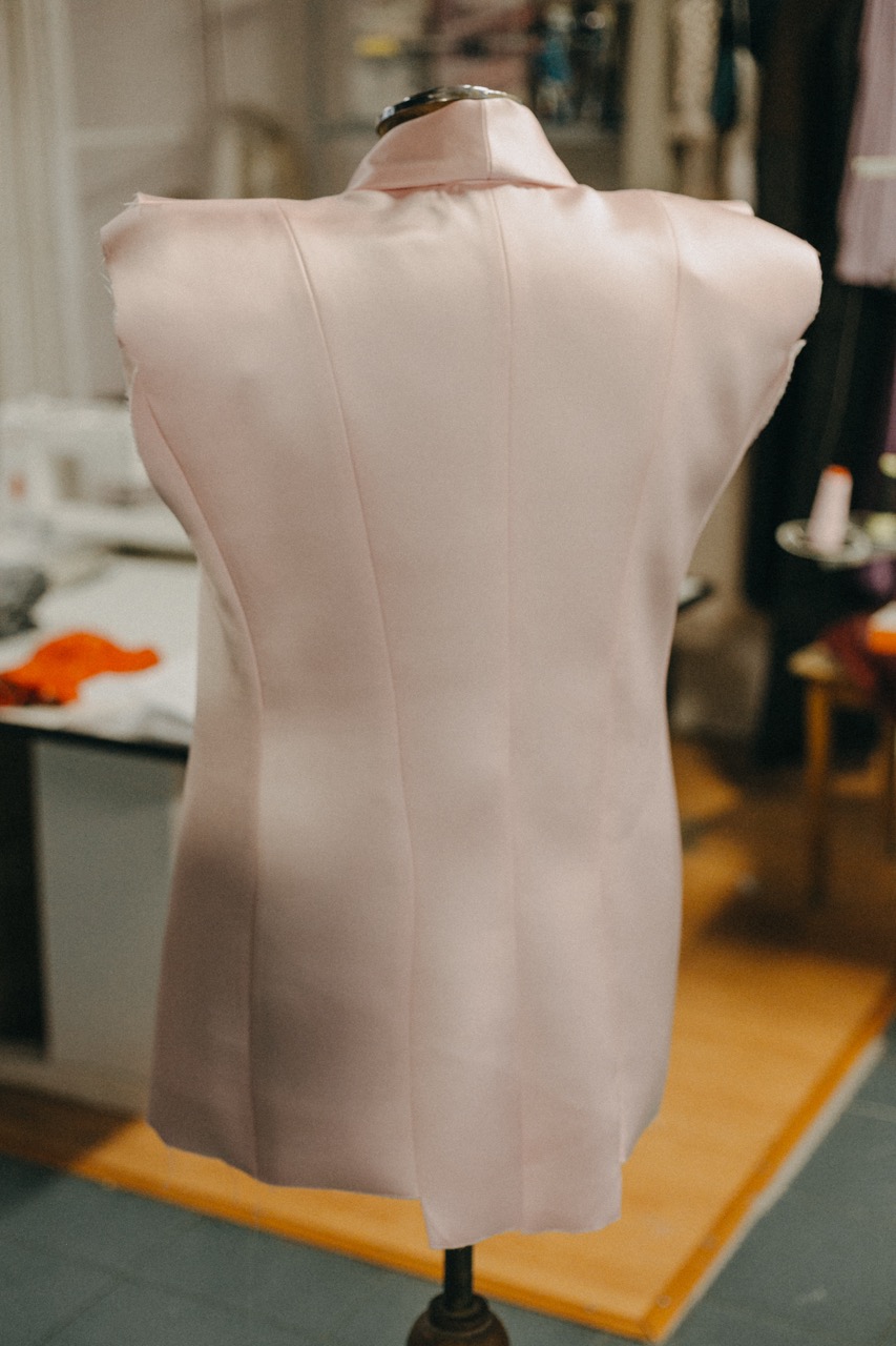 Saco rosa de crepe satén con solapa en punta de espada sobre maniquí en Atelier Molina